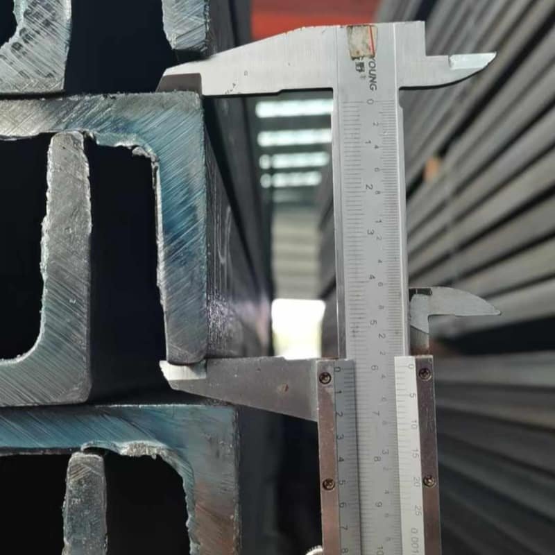 Quality inspection measuring the flange thickness of a Structural Steel U-Beam with a caliper to ensure precise dimensions.